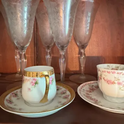 Sale Photo Thumbnail #393: Collection of vintage floral glassware and porcelain teacups with saucers, featuring etched crystal stemware and gold-trimmed hand-painted teacups.