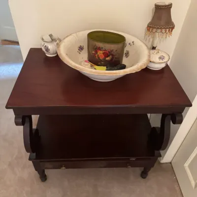 Sale Photo Thumbnail #143: Dark wood two-tier side table with scrolled side supports and a bottom drawer, displayed with decorative porcelain wash basins and small table lamps.