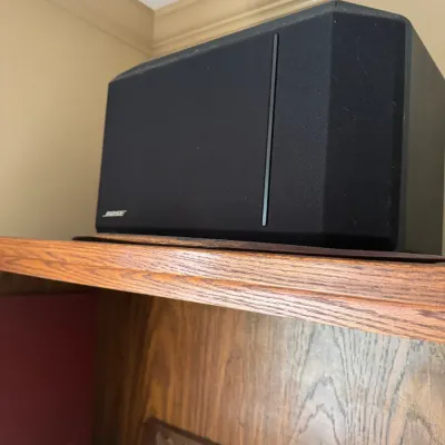 Sale Photo Thumbnail #41: Black Bose Direct/Reflecting speaker with mesh grille, sitting on a wooden shelf.