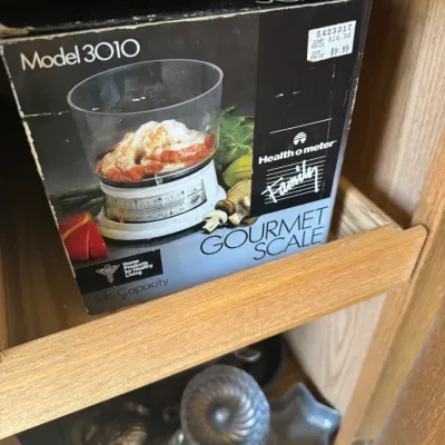 Sale Photo Thumbnail #224: Vintage Health o meter Family Gourmet Scale Model 3010 in its original box, featured on a wooden cabinet shelf.