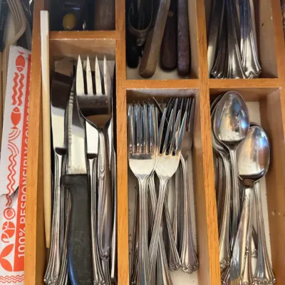 Sale Photo Thumbnail #31: Assorted stainless steel flatware and kitchen utensils organized inside a wooden drawer divider tray.