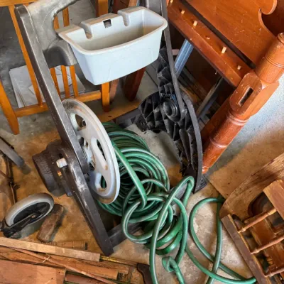 Sale Photo Thumbnail #202: Portable plastic garden hose reel cart with attached storage caddy and coiled green garden hose.