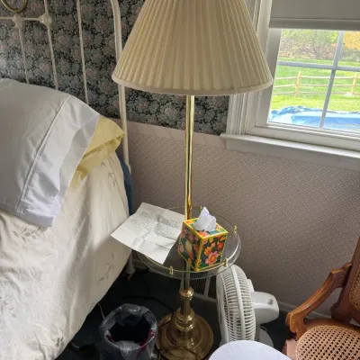 Sale Photo Thumbnail #138: Brass floor lamp featuring an integrated glass-top tray table and pleated fabric shade, set alongside a white iron bed frame.