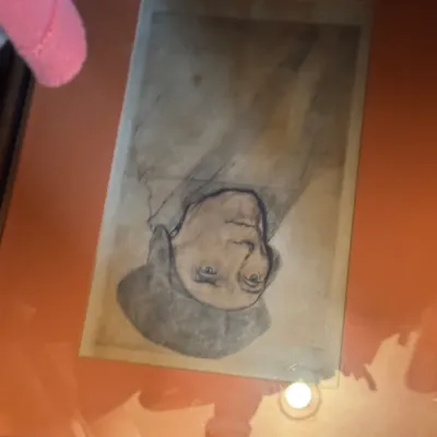 Sale Photo Thumbnail #103: Framed upside-down portrait sketch of a man wearing a soft hat, set in an orange mat with a dark wooden frame.