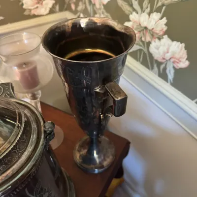 Sale Photo Thumbnail #388: Vintage silver-plated trophy urn featuring a single angular handle, set alongside other tarnish-patinated silver decor pieces.