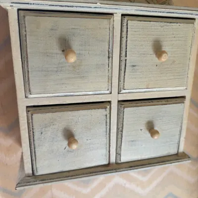 Sale Photo Thumbnail #16: Rustic wall-mounted wooden cabinet featuring four small drawers with round knobs and carved floral pediment detail.