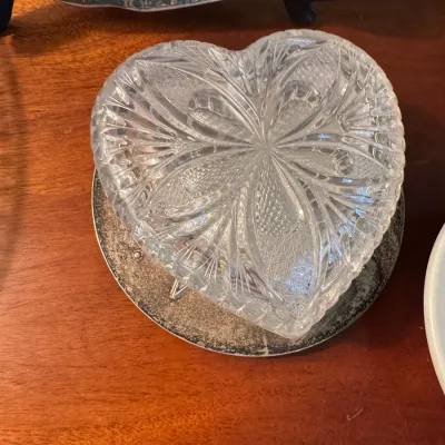 Sale Photo Thumbnail #342: Heart-shaped cut crystal trinket dish featuring intricate starburst and fan patterns, displayed on a tarnished silver-tone coaster.