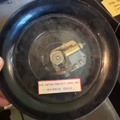 Sale Photo Thumbnail #337: Vintage musical dish featuring an exposed wind-up mechanism, labeled for The Aetna Freight Lines, Inc. of Warren, Ohio.