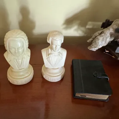 Sale Photo Thumbnail #324: Two vintage composite bust sculptures of Bach and Schubert paired with a small black leather-bound book.