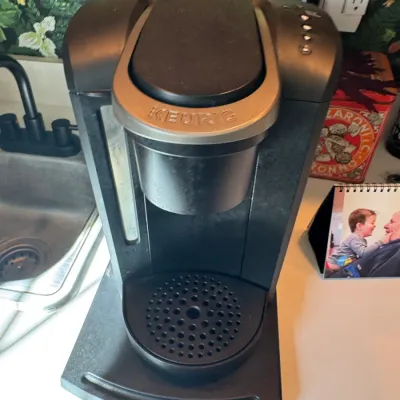 Sale Photo Thumbnail #246: Black Keurig single-serve K-Cup coffee maker, sitting on a kitchen countertop.