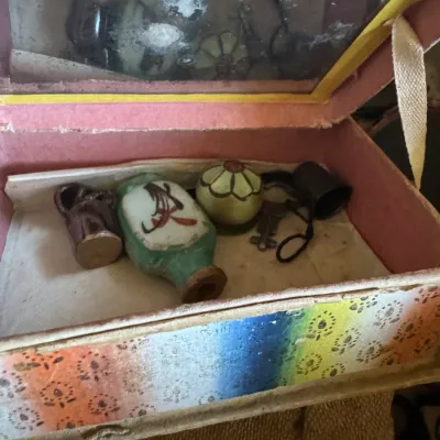 Sale Photo Thumbnail #57: Vintage paper-covered box with an interior mirror, containing small collectibles including a painted ceramic bottle, miniature jug, thimble, key, and round vessel.