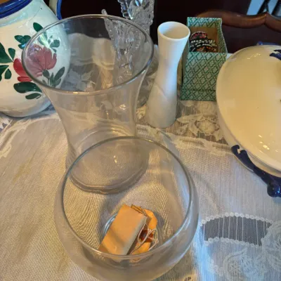 Sale Photo Thumbnail #419: Collection of tabletop glassware, ceramics, and decor items including clear glass vases, a white porcelain bud vase, and a hand-painted floral pitcher.