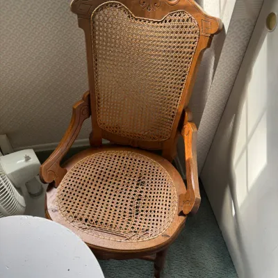 Sale Photo Thumbnail #139: Vintage carved wooden armchair with woven cane back and seat, featuring spade-motif detailing along the crest.