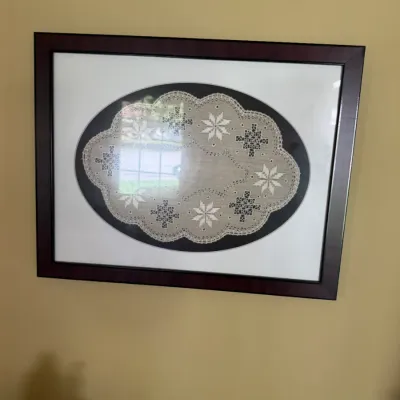 Sale Photo Thumbnail #321: Framed Hardanger embroidery doily featuring geometric snowflake motifs and an oval mat board, displayed in a dark wood frame under glass.