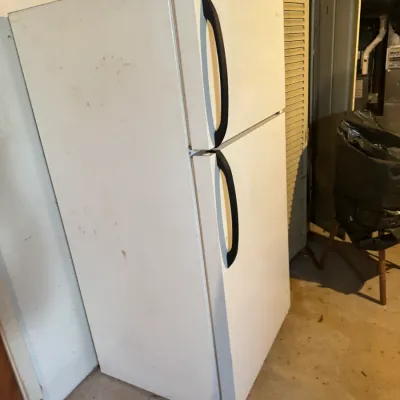 Sale Photo Thumbnail #75: White top-freezer refrigerator with black door handles, showing minor surface scuffs from use.