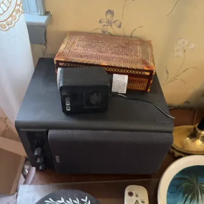 Sale Photo Thumbnail #186: Black RCA stereo speaker with power adapter, alongside an inlaid wooden trinket box and assorted decor items.
