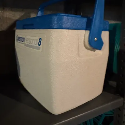 Sale Photo Thumbnail #84: Vintage Coleman Personal 8 small hard-sided cooler in white and blue, featuring an integrated carrying handle.