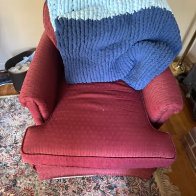Sale Photo Thumbnail #285: Red upholstered armchair draped with a thick, hand-knit chenille blanket in navy and light blue stripes.