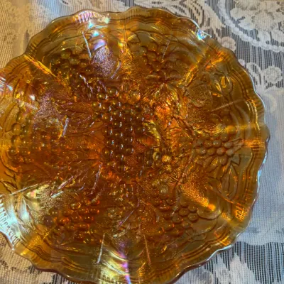 Sale Photo Thumbnail #64: Vintage marigold carnival glass bowl featuring a embossed grape and vine pattern with a scalloped edge.