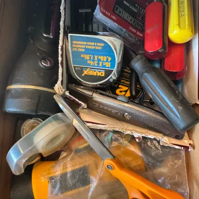 Sale Photo Thumbnail #230: Junk drawer filled with assorted household tools and supplies, including Fiskars scissors, tape measures, screwdrivers, flashlights, and a utility knife.