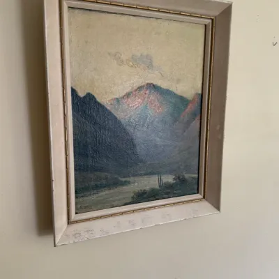 Sale Photo Thumbnail #121: Framed vintage oil painting depicting a desert landscape with mountains and saguaro cacti, housed in an off-white wooden frame with gold trim.