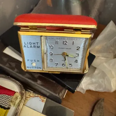 Sale Photo Thumbnail #20: Vintage Phinney-Walker red folding travel alarm clock with a brass case and built-in light feature.