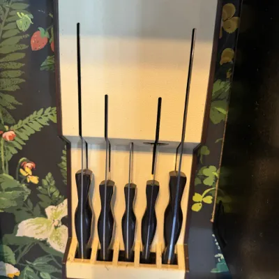 Sale Photo Thumbnail #272: Vintage wall-mounted knife block with five contoured black-handled kitchen knives, mid-century style.