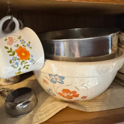 Sale Photo Thumbnail #257: Vintage ceramic mixing bowl with floral design, stored on a cabinet shelf with a matching mug and stainless steel inserts.