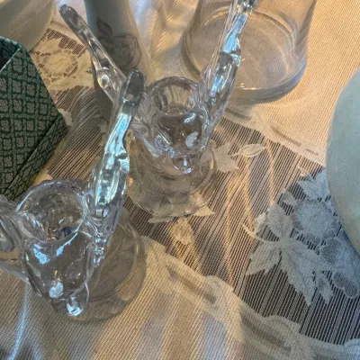 Sale Photo Thumbnail #408: Pair of vintage clear pressed glass bird figurine candle holders displayed on a floral lace tablecloth.