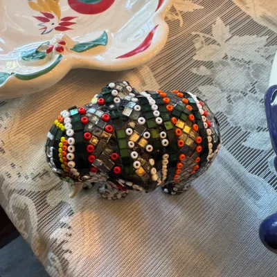 Sale Photo Thumbnail #407: Handcrafted mosaic and beaded elephant figurine featuring colorful glass tiles and seed beads, displayed alongside a hand-painted rooster ceramic platter.