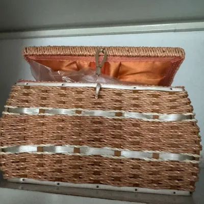 Sale Photo Thumbnail #126: Vintage woven wicker sewing basket featuring white ribbon accents, a loop-and-peg closure, and a satin-lined interior lid.