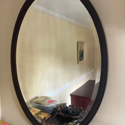 Sale Photo Thumbnail #119: Large oval wall mirror in a dark carved wood frame, reflecting a hallway interior.