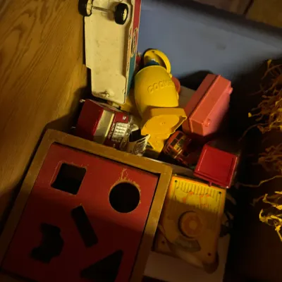 Sale Photo Thumbnail #3: Assortment of vintage plastic and wooden children's toys stored inside a cabinet, including a shape-sorter box, toy vehicles, and a Fisher-Price Cookie Monster toy.