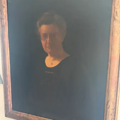 Sale Photo Thumbnail #39: Early 20th-century framed oil painting depicting a portrait of a woman wearing glasses, housed in a carved gilded wood frame.