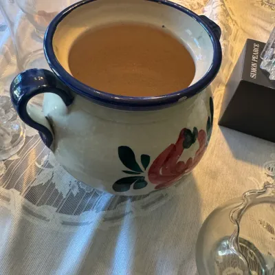 Sale Photo Thumbnail #409: Vintage hand-painted ceramic chamber pot featuring dark blue trim and handles with red floral motif accents.