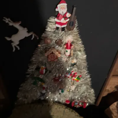 Sale Photo Thumbnail #79: Framed vintage holiday shadowbox art featuring a silver tinsel Christmas tree adorned with miniature ornaments, a guitar-playing Santa topper, and a leaping reindeer silhouette.