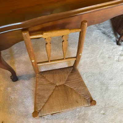 Sale Photo Thumbnail #329: Vintage miniature or child-sized wooden ladder-back chair featuring a woven rush seat, styled next to a polished wooden table.