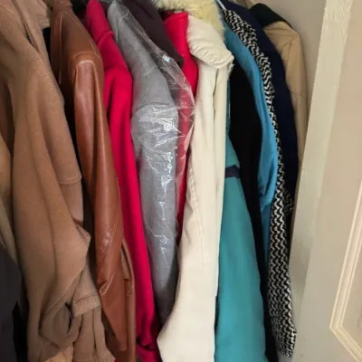 Sale Photo Thumbnail #278: Collection of vintage women's outerwear hanging in a closet, including a brown leather jacket, wool coats, and a parka with a faux fur collar.