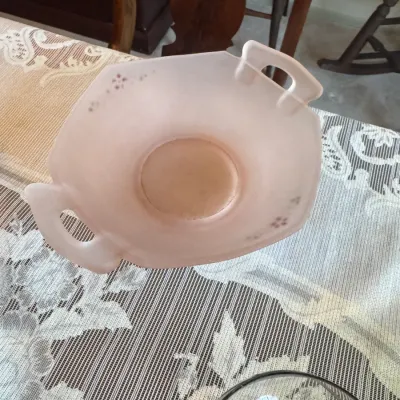 Sale Photo Thumbnail #412: Vintage pink frosted glass double-handled dish featuring hand-painted floral accents, resting on a patterned tablecloth.