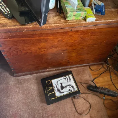 Sale Photo Thumbnail #161: Rustic antique wooden trunk with dovetail joints, serving as a table surface for electronics and household accessories.
