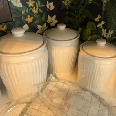 Sale Photo Thumbnail #267: Set of three off-white ribbed ceramic kitchen canisters with lids, shown alongside glass pie dishes.