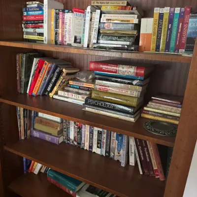 Sale Photo Thumbnail #117: Tall wood bookcase filled with various hardcovers and paperbacks, including fiction, psychology textbooks, and religious non-fiction.