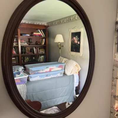 Sale Photo Thumbnail #107: Large oval wall mirror in a dark wood frame, reflecting a bedroom interior.