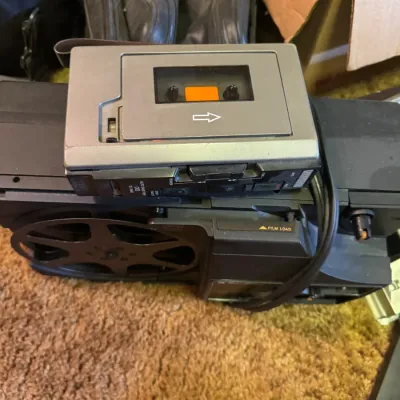 Sale Photo Thumbnail #100: Vintage portable microcassette recorder resting on top of a 8mm or Super 8 film projector.