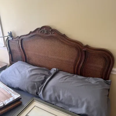 Sale Photo Thumbnail #123: French Provincial style wooden headboard featuring woven cane panel inserts and carved crest detailing.