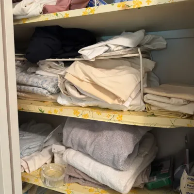Sale Photo Thumbnail #142: Linen closet filled with assorted folded bed sheets, pillowcases, and bath towels organized on floral-lined shelves.