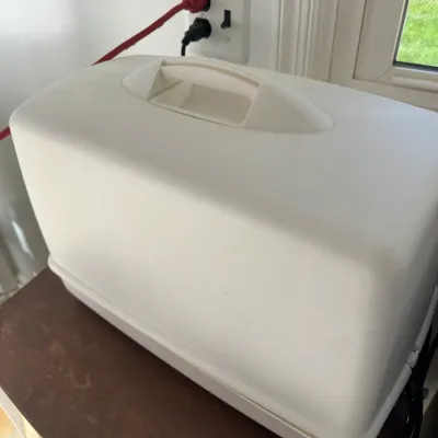 Sale Photo Thumbnail #222: Off-white molded plastic carrying case for a portable sewing machine, featuring a recessed top handle.