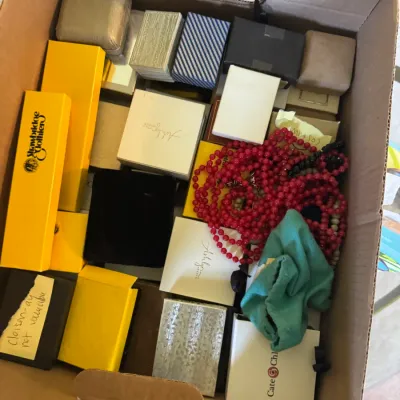 Sale Photo Thumbnail #374: Cardboard box filled with assorted small jewelry gift boxes, red beaded necklaces, and a turquoise fabric pouch.