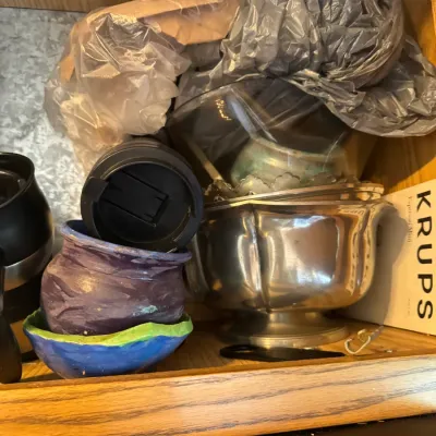 Sale Photo Thumbnail #268: Selection of kitchenware and decorative items stored in a cabinet, including a polished metal bowl, handmade ceramic pots, travel mug lids, and a Krups box.