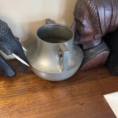 Sale Photo Thumbnail #316: Vintage metal vase with angular handles, flanked by a carved wooden elephant and a carved wooden bust.